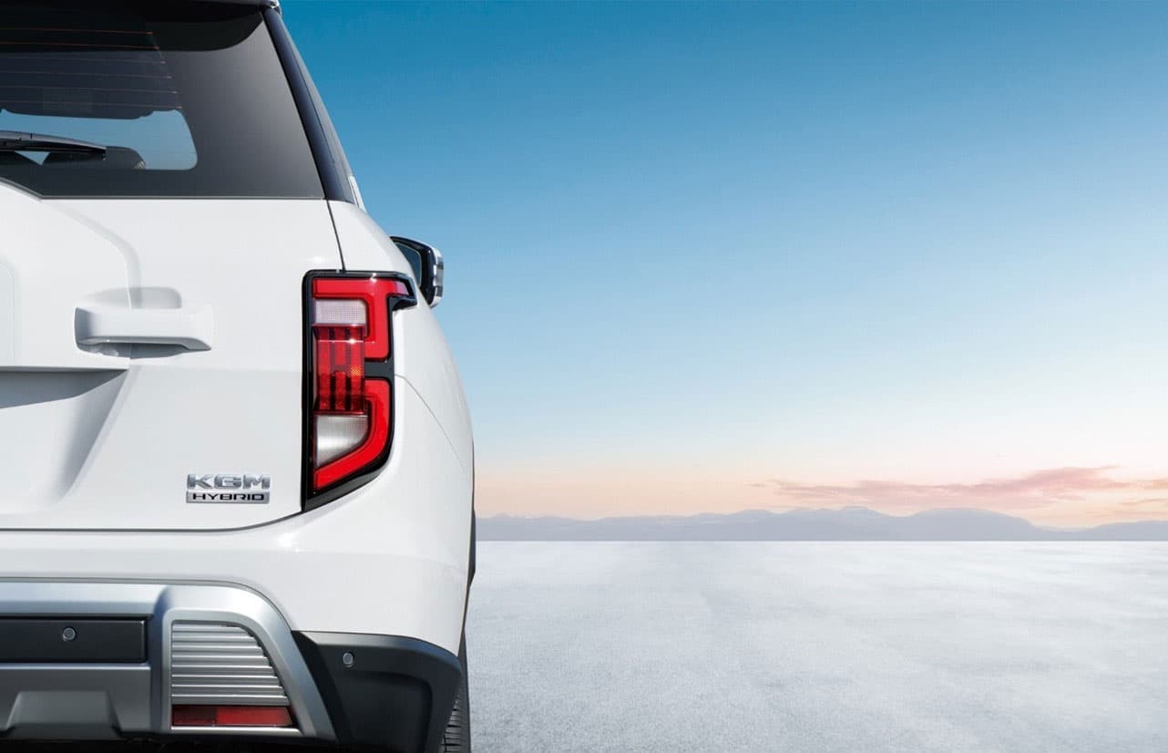 Rear view of a white KGM Torres Hybrid on a vast, icy landscape under a clear sky, highlighting the taillight and hybrid badge.