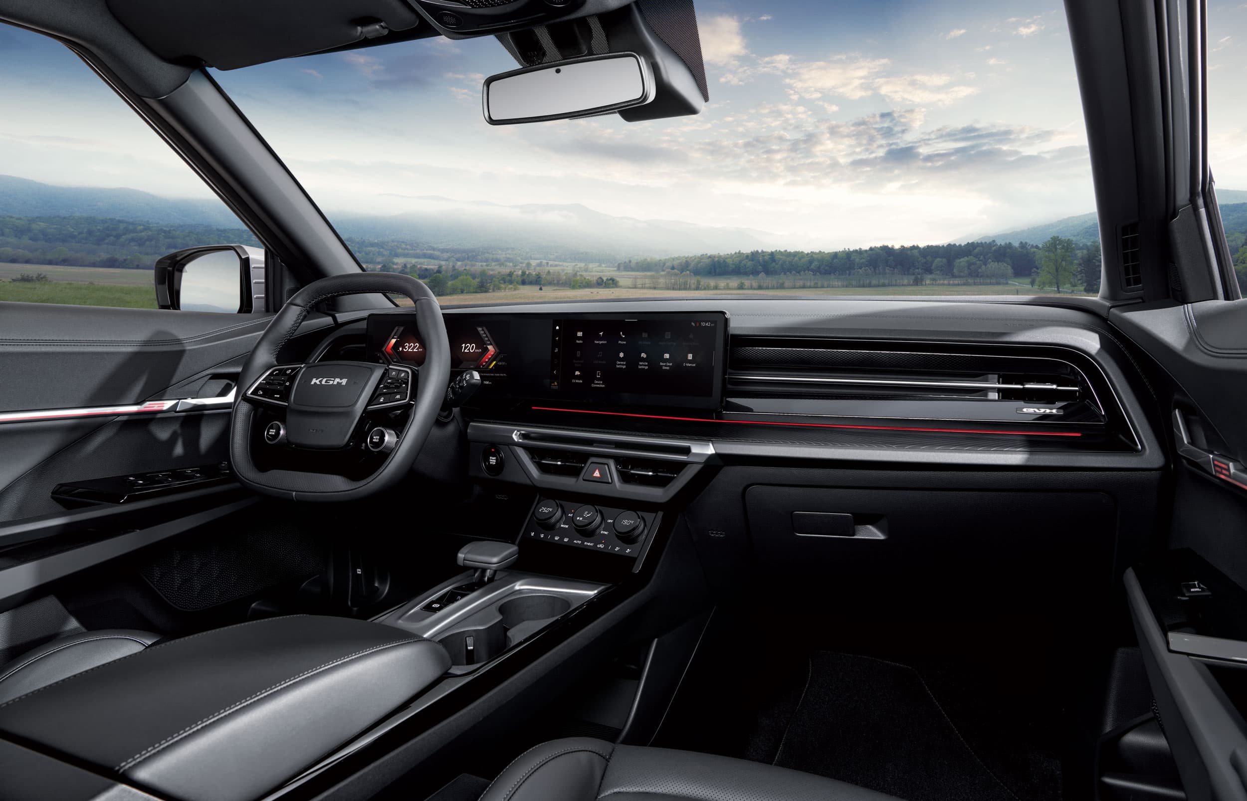 Modern KGM Torres EVX interior with a sleek dashboard, digital display, and a scenic view of mountains and fields through the windshield.